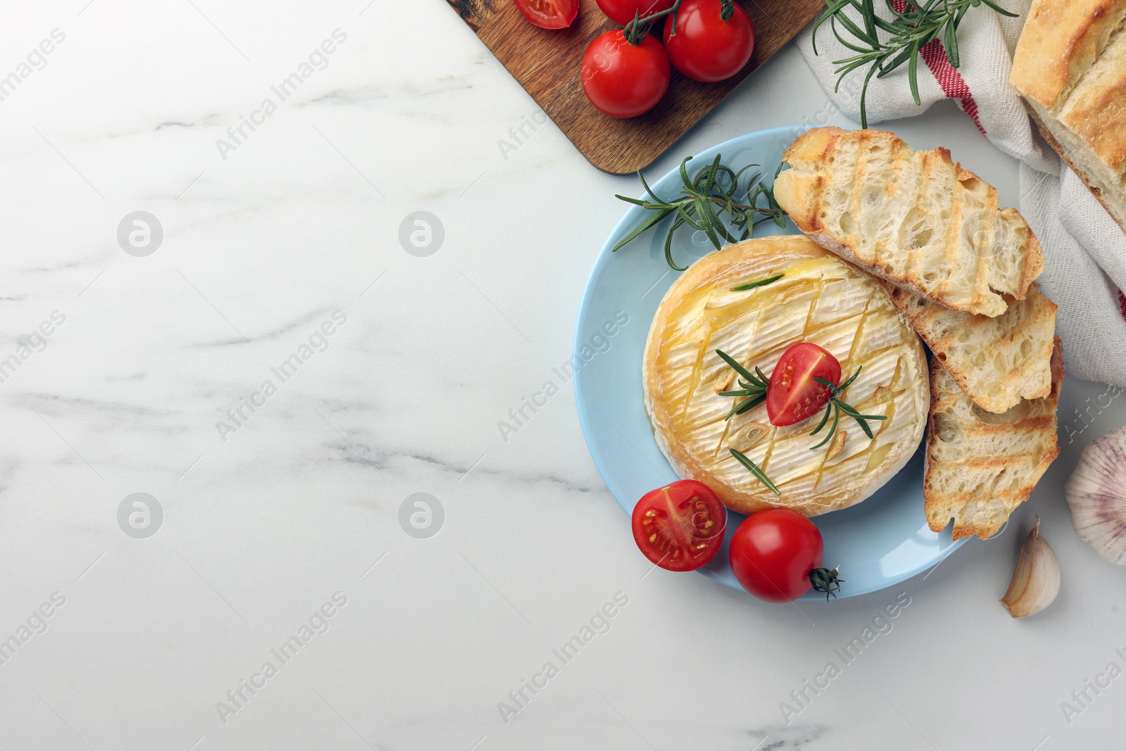 Photo of Tasty baked brie cheese served on white marble table, flat lay. Space for text