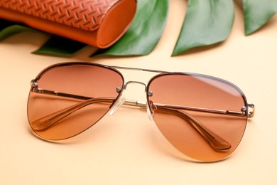 Photo of Stylish elegant sunglasses on beige background, closeup