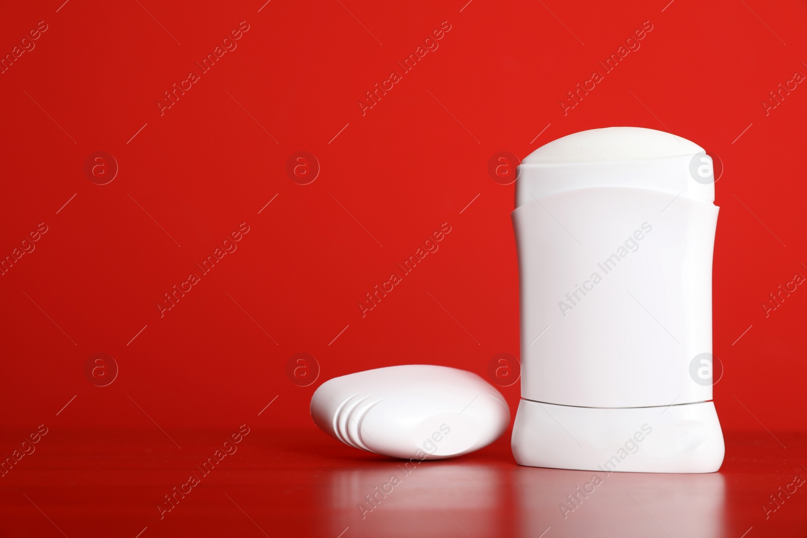 Photo of Stick deodorant on table against red background. Space for design