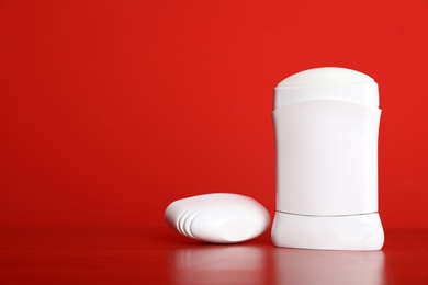 Stick deodorant on table against red background. Space for design