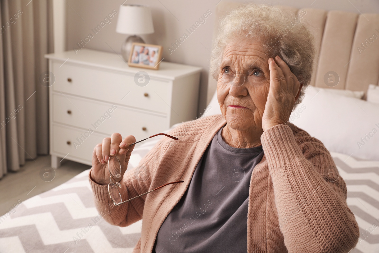 Photo of Senior woman with headache in bedroom at home