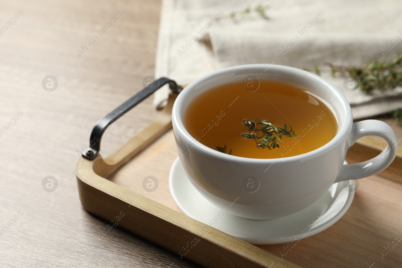 Photo of Cup of fresh thyme tea on wooden table, closeup