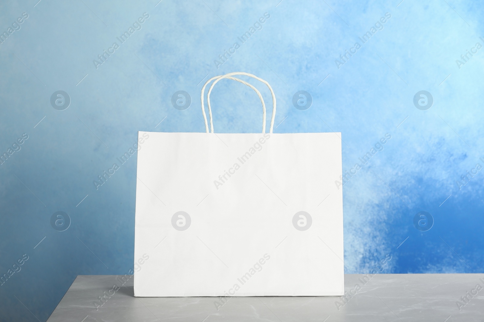 Photo of Mockup of paper shopping bag on table against color background