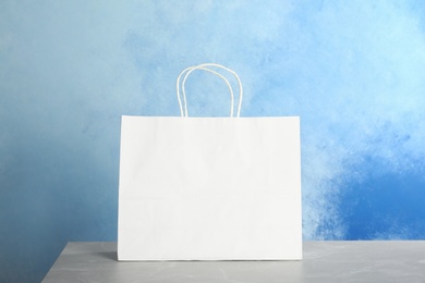 Photo of Mockup of paper shopping bag on table against color background