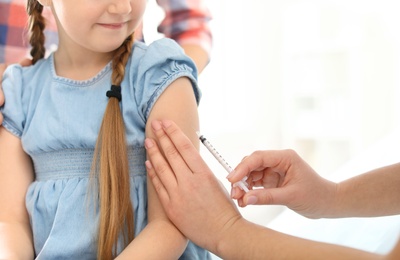 Photo of Children's doctor vaccinating little girl in hospital, closeup