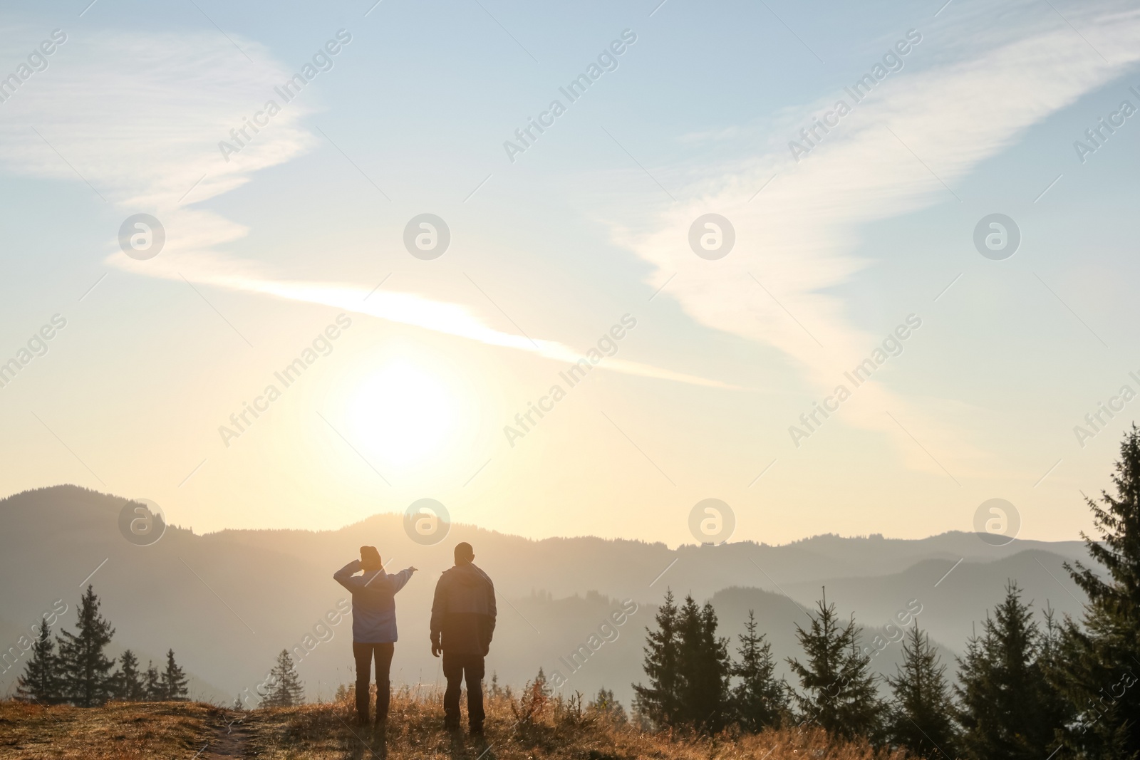 Photo of Couple enjoying sunrise in mountains, back view. Space for text