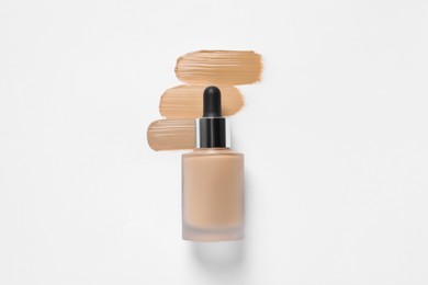 Photo of Liquid foundation and swatches on white background, top view