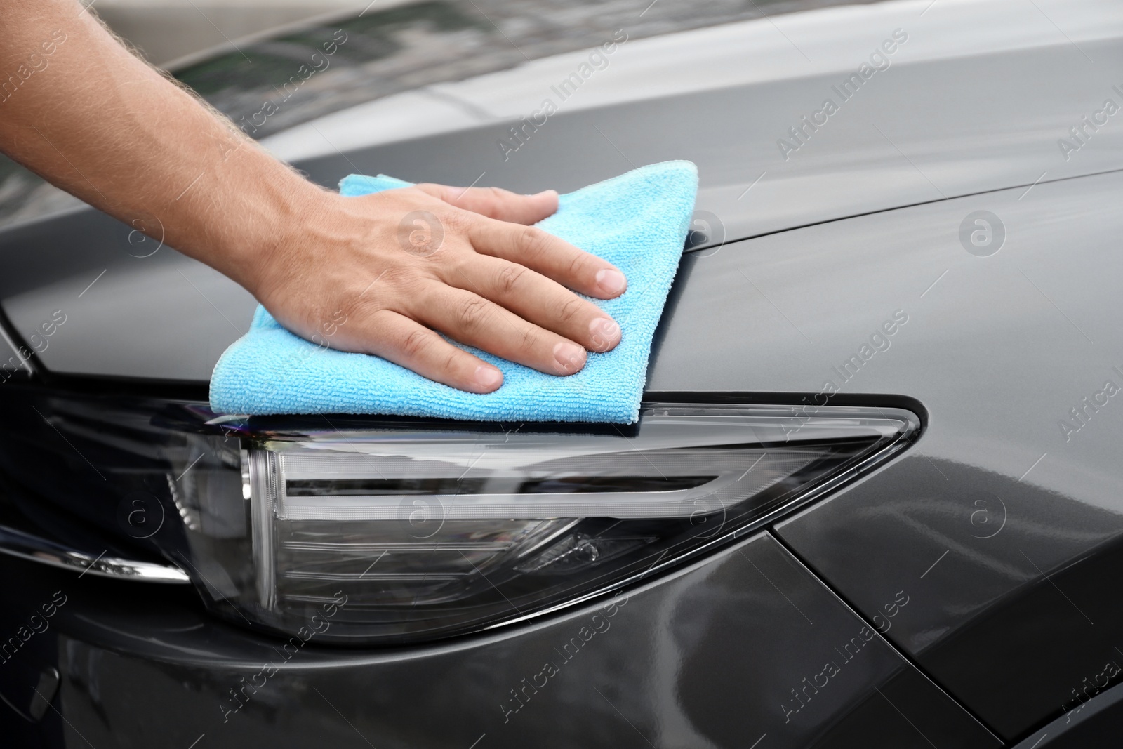 Photo of Man washing car headlight with rag, closeup