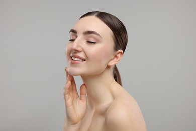 Smiling woman touching her chin on grey background. Space for text