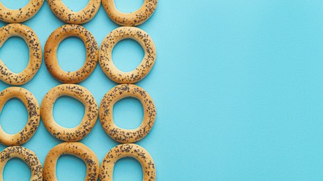 Photo of Many delicious ring shaped Sushki (dry bagels) on light blue background, flat lay. Space for text