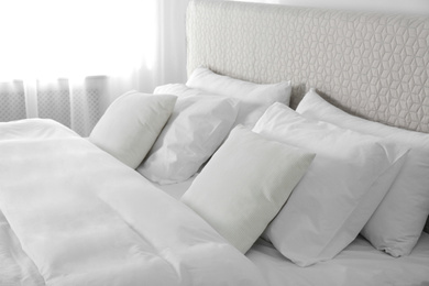 Photo of Bed with soft fluffy pillows at home