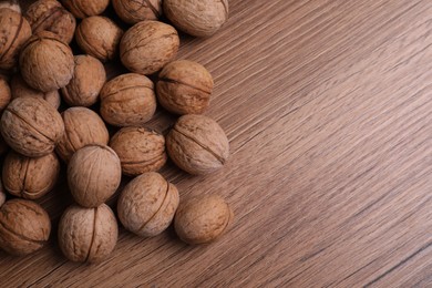 Photo of Pile of ripe walnuts on wooden table. Space for text