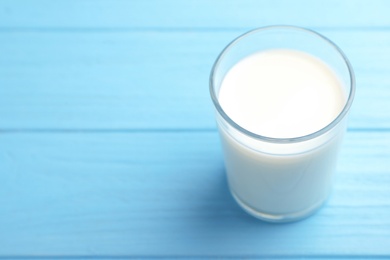 Glass of fresh milk on color wooden table. Space for text