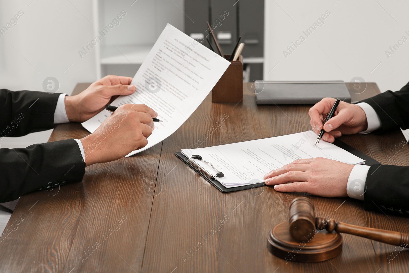 Photo of Law and justice. Lawyers working with documents at wooden table in office, closeup