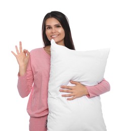 Happy young woman with soft pillow showing okay gesture on white background