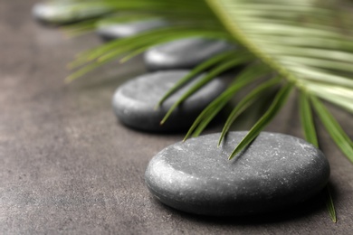 Spa stones and green leaf on grey background. Space for text