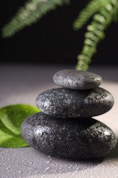 Photo of Wet spa stones and green leaves on grey background