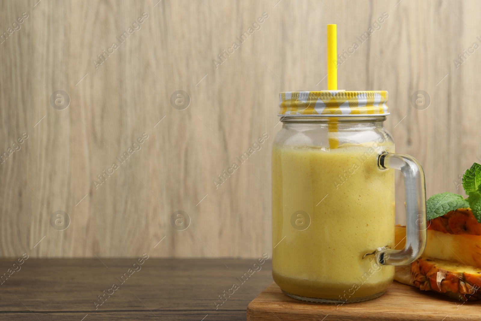 Photo of Tasty pineapple smoothie, mint and sliced fruit on wooden table. Space for text