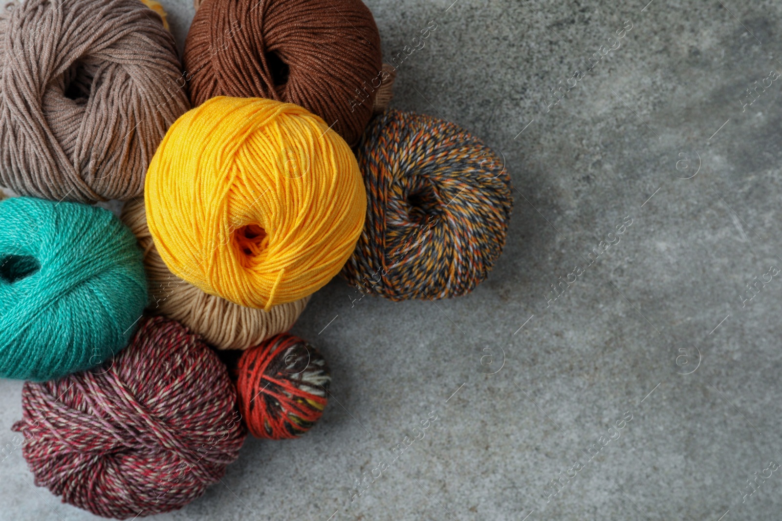 Photo of Many different soft woolen yarns on grey table, flat lay. Space for text