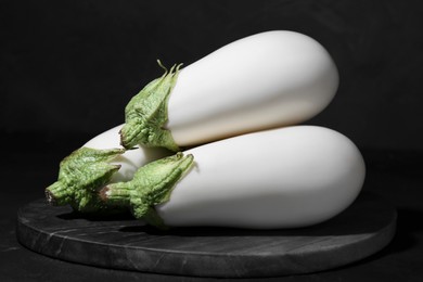 Three fresh white eggplants on black table