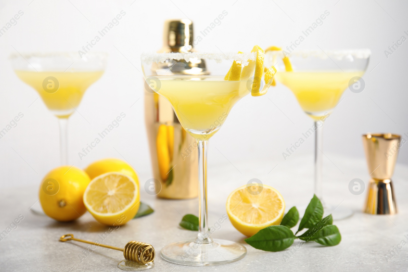 Photo of Delicious bee's knees cocktails and ingredients on light grey table