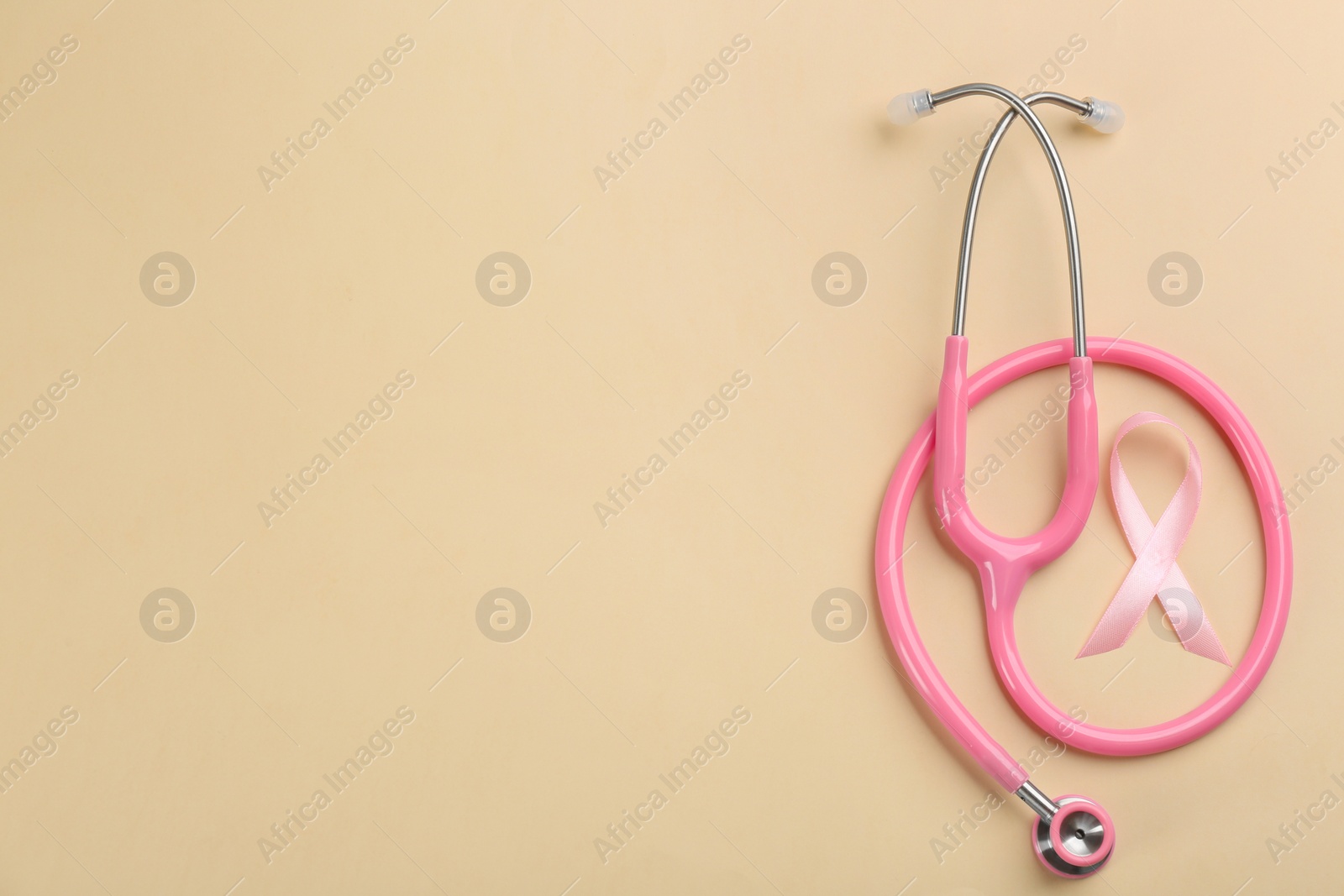 Photo of Pink ribbon and stethoscope on beige background, flat lay with space for text. Breast cancer concept