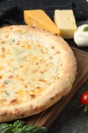 Delicious cheese pizza and ingredients on dark grey table