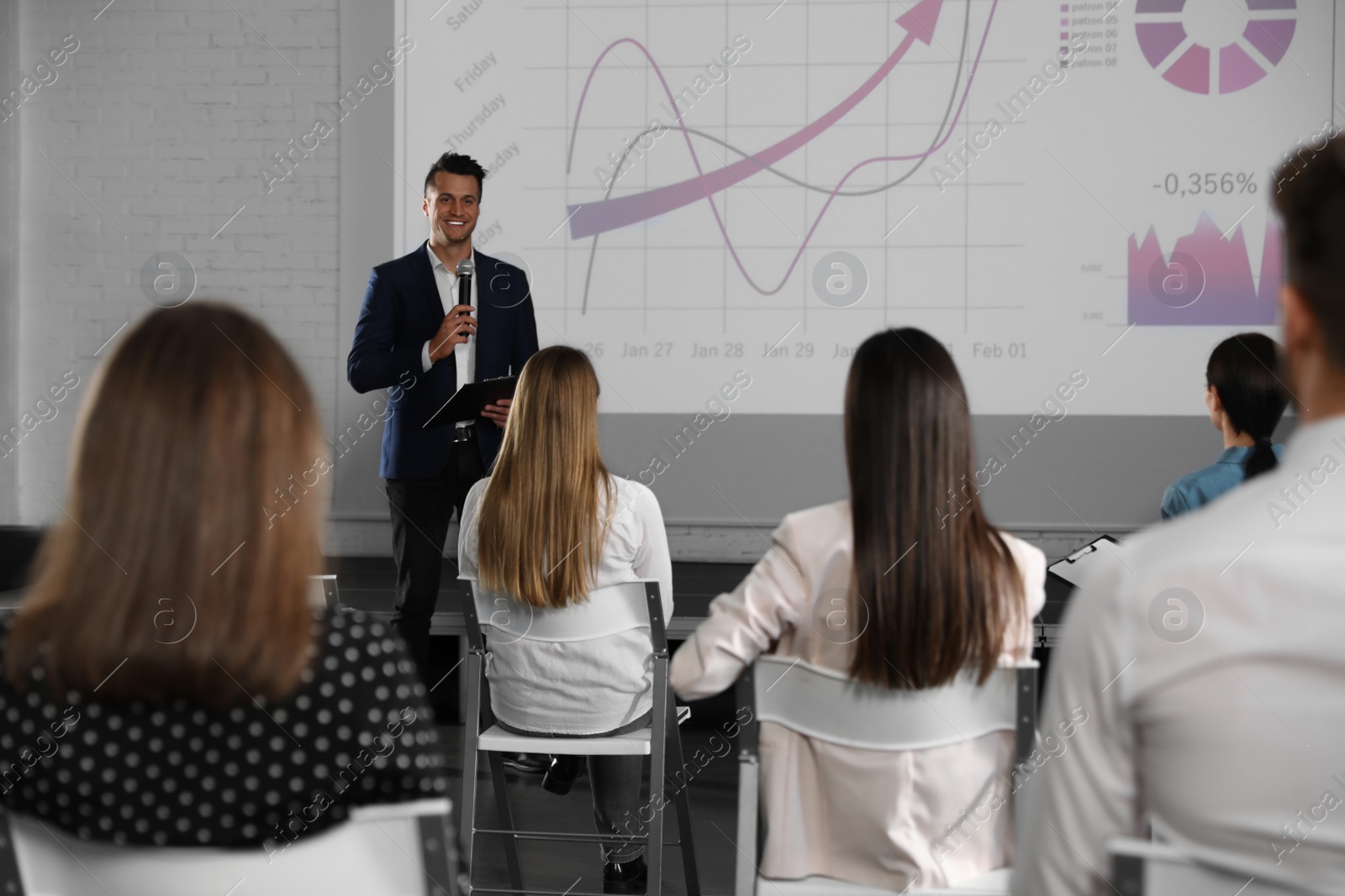 Photo of Male business trainer giving lecture in conference room with projection screen