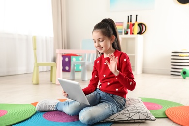 Photo of Little girl using video chat on tablet in playroom