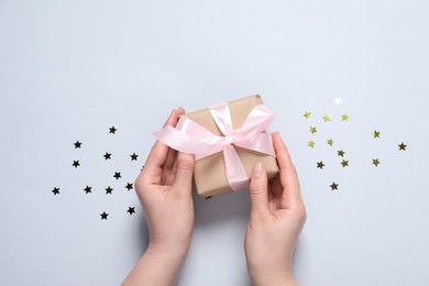 Photo of Woman with gift box and confetti on white background, top view