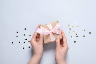 Woman with gift box and confetti on white background, top view