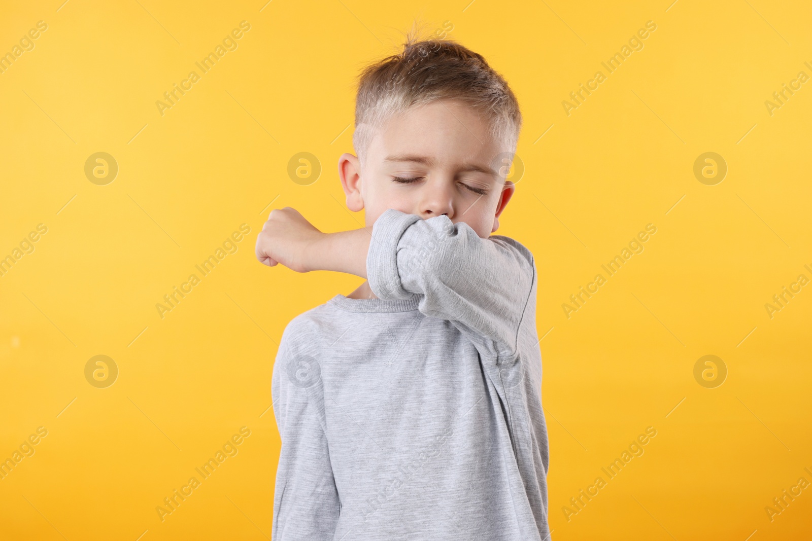 Photo of Sick boy coughing on yellow background. Cold symptoms