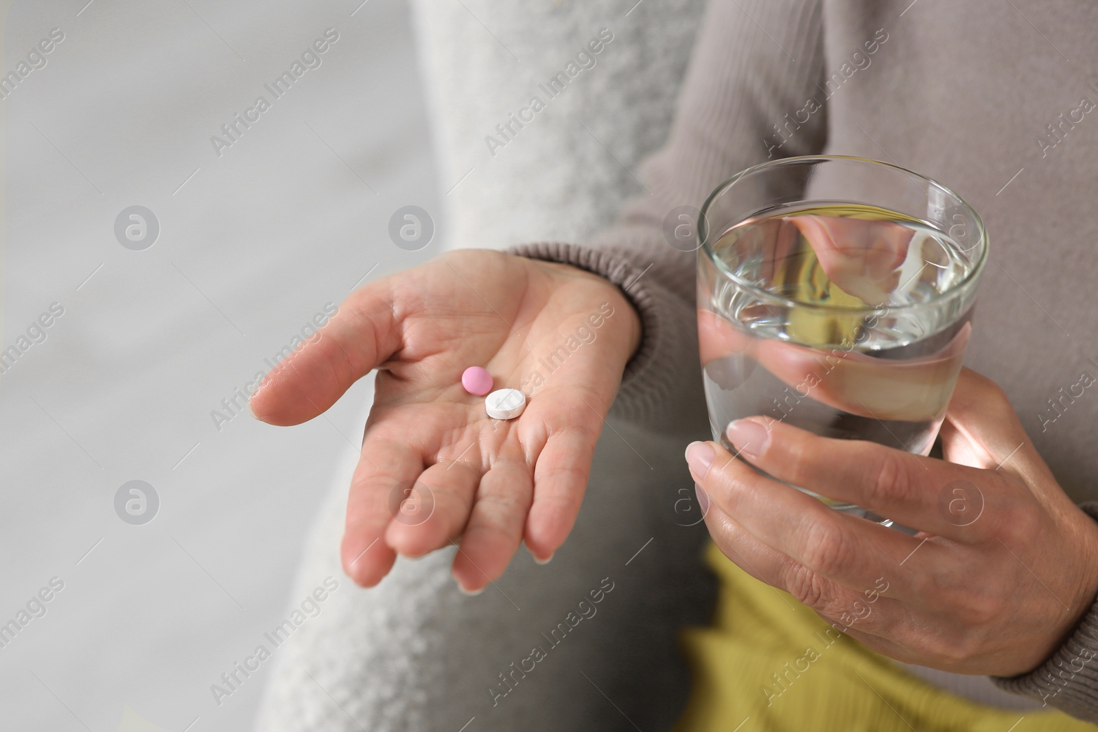 Photo of Senior woman with glass of water and pills indoors, closeup