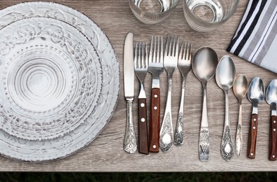 Photo of Different tableware and cutlery on wooden table, flat lay. Garage sale