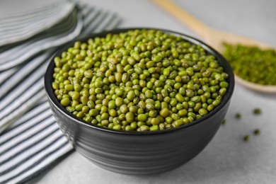 Photo of Bowl with green mung beans on grey table, closeup