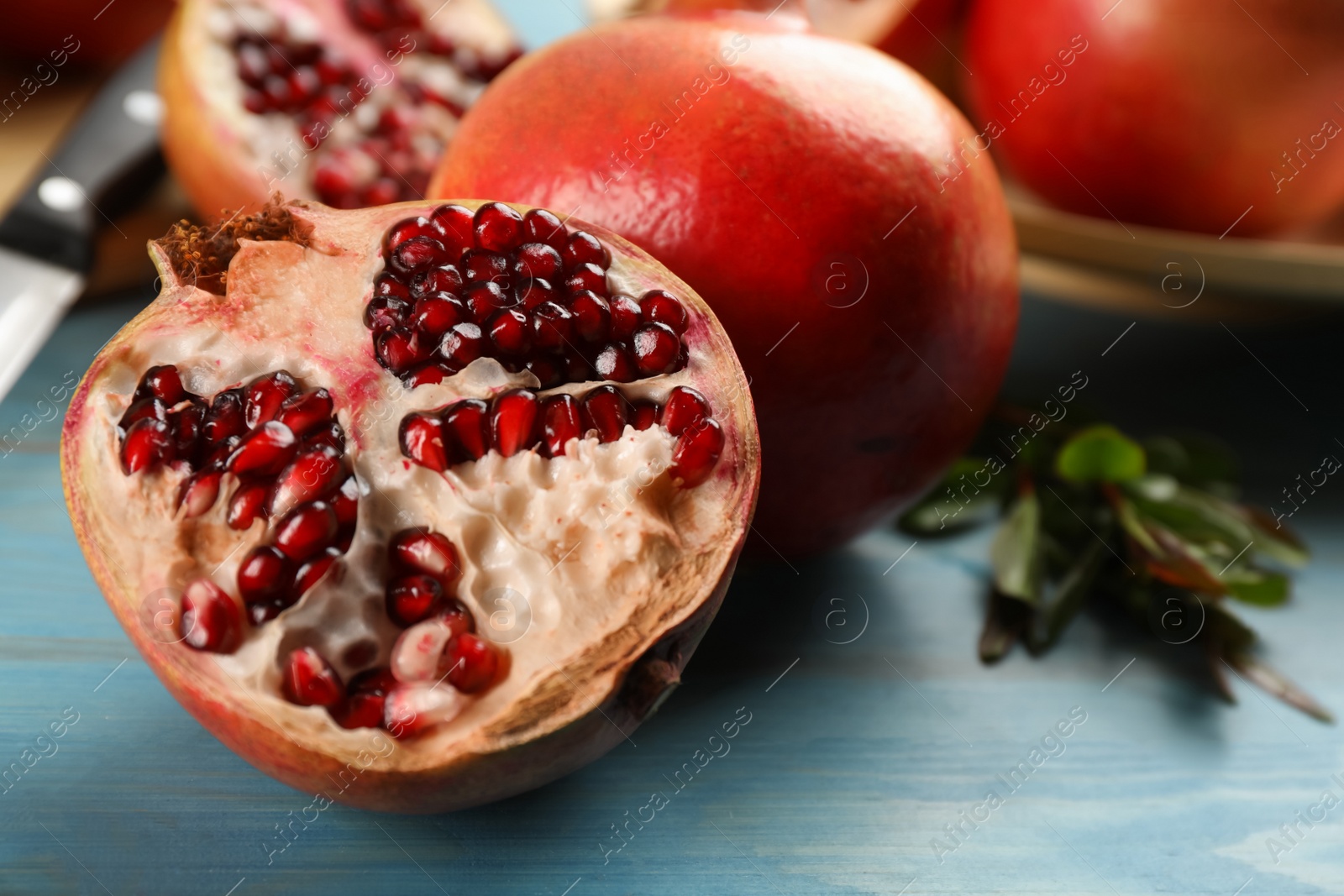 Photo of Ripe pomegranates on light blue wooden table, closeup. Space for text