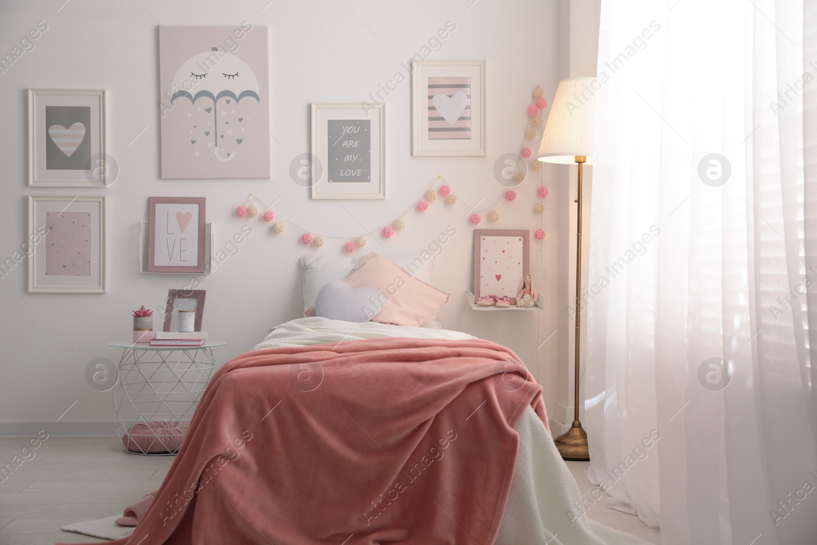 Photo of Stylish child's room interior with beautiful pictures and comfortable bed