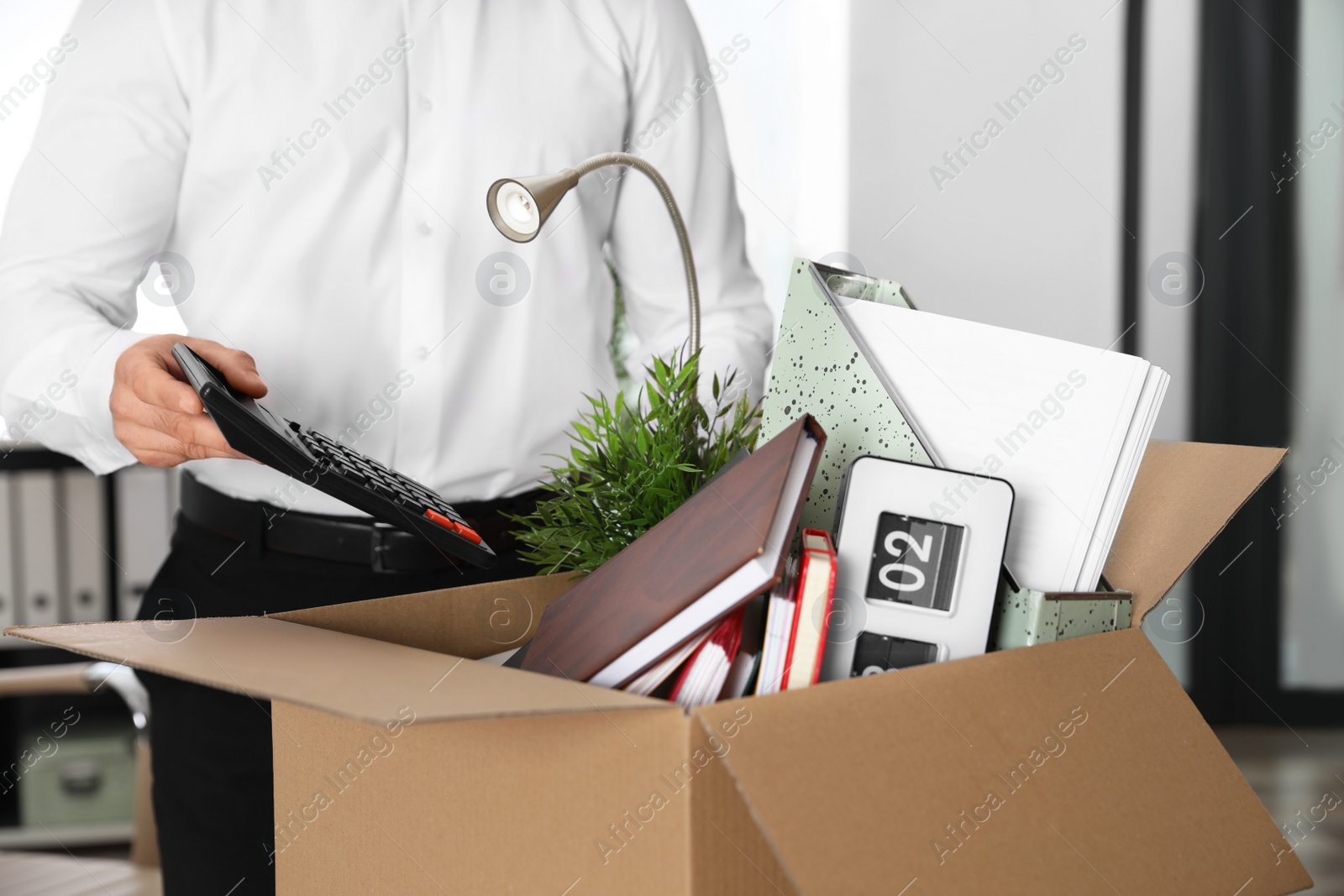 Photo of Young man packing stuff in box at office, closeup