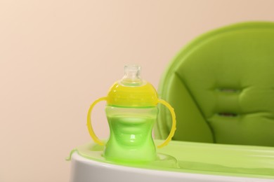 High chair with feeding bottle of infant formula on light green tray