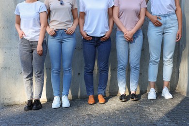 Photo of Women in stylish jeans near grey wall outdoors, closeup
