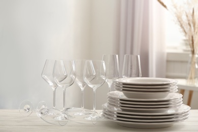 Photo of Set of clean dishware and wineglasses on white table indoors