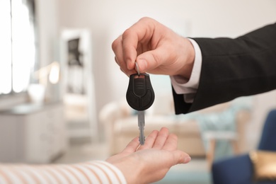 Photo of Man giving car key to woman indoors, closeup. Space for text