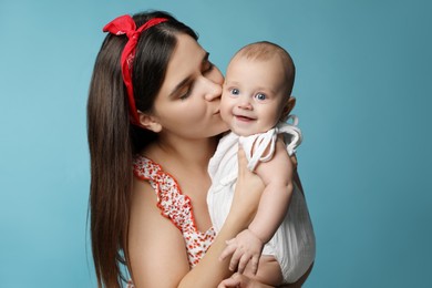 Photo of Beautiful mother kissing her cute baby on turquoise background