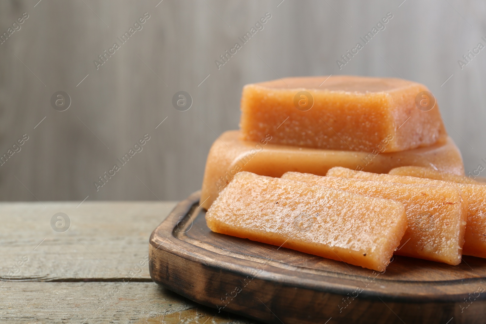 Photo of Tasty sweet quince paste on wooden table, closeup. Space for text