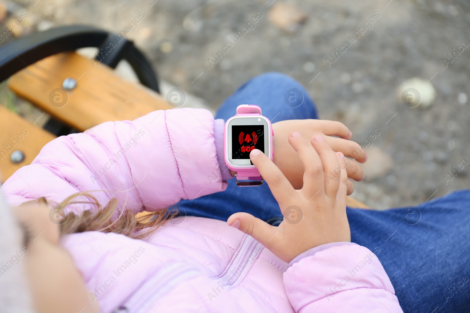 Image of Little girl using SOS function on smartwatch outdoors, closeup