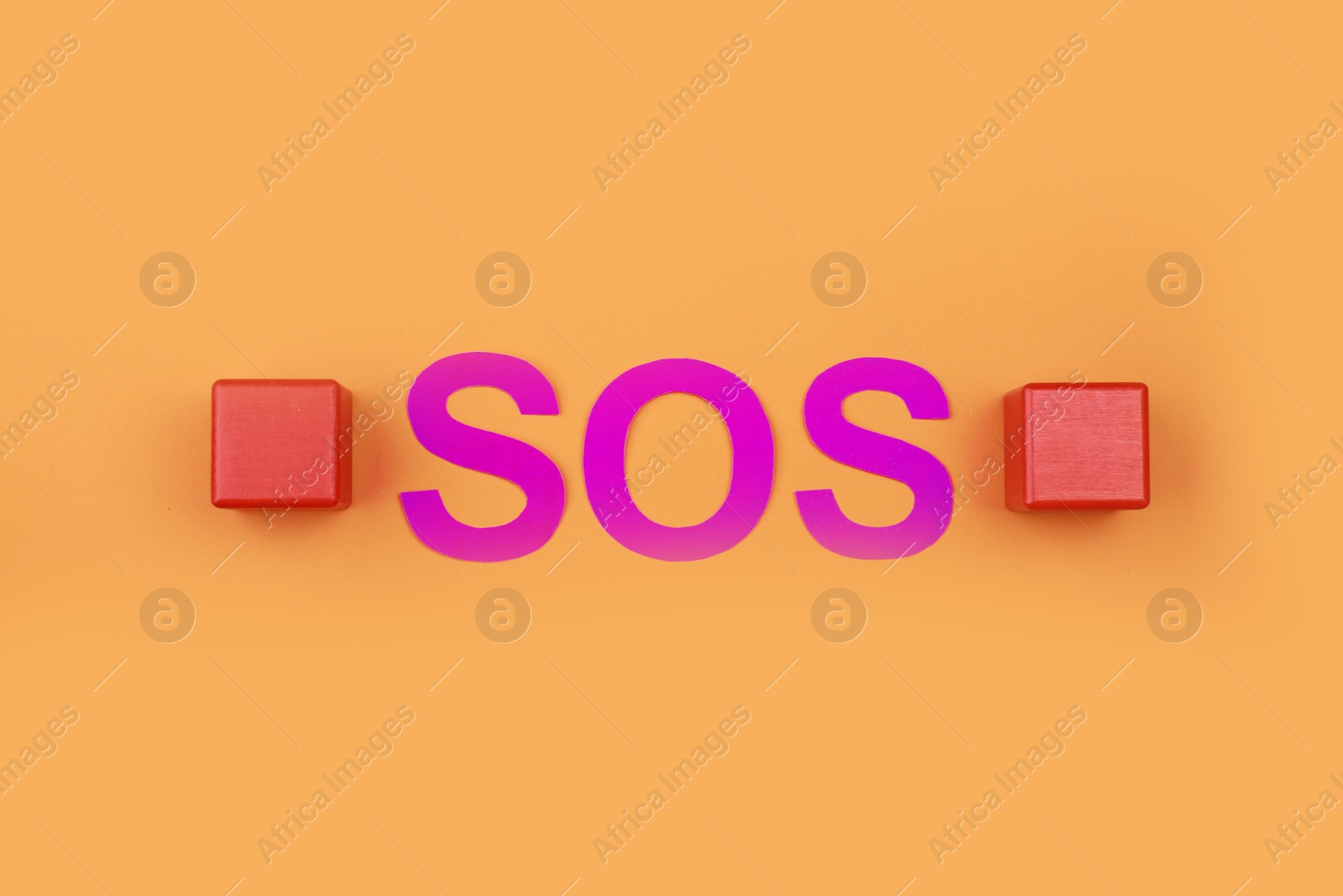 Photo of Abbreviation SOS made of paper letters and wooden cubes on orange background, flat lay