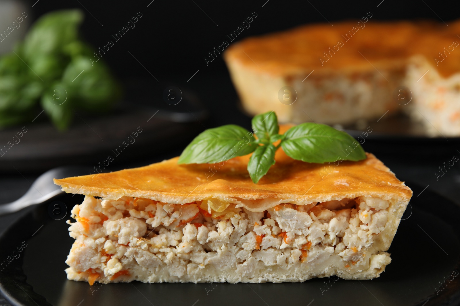 Photo of Piece of delicious pie with meat and basil in plate, closeup