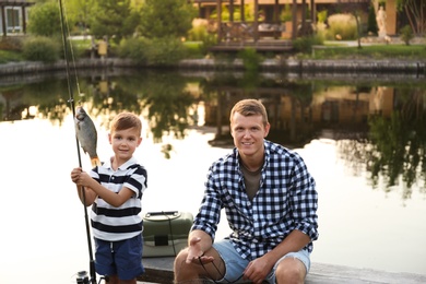 Dad and son fishing together on sunny day