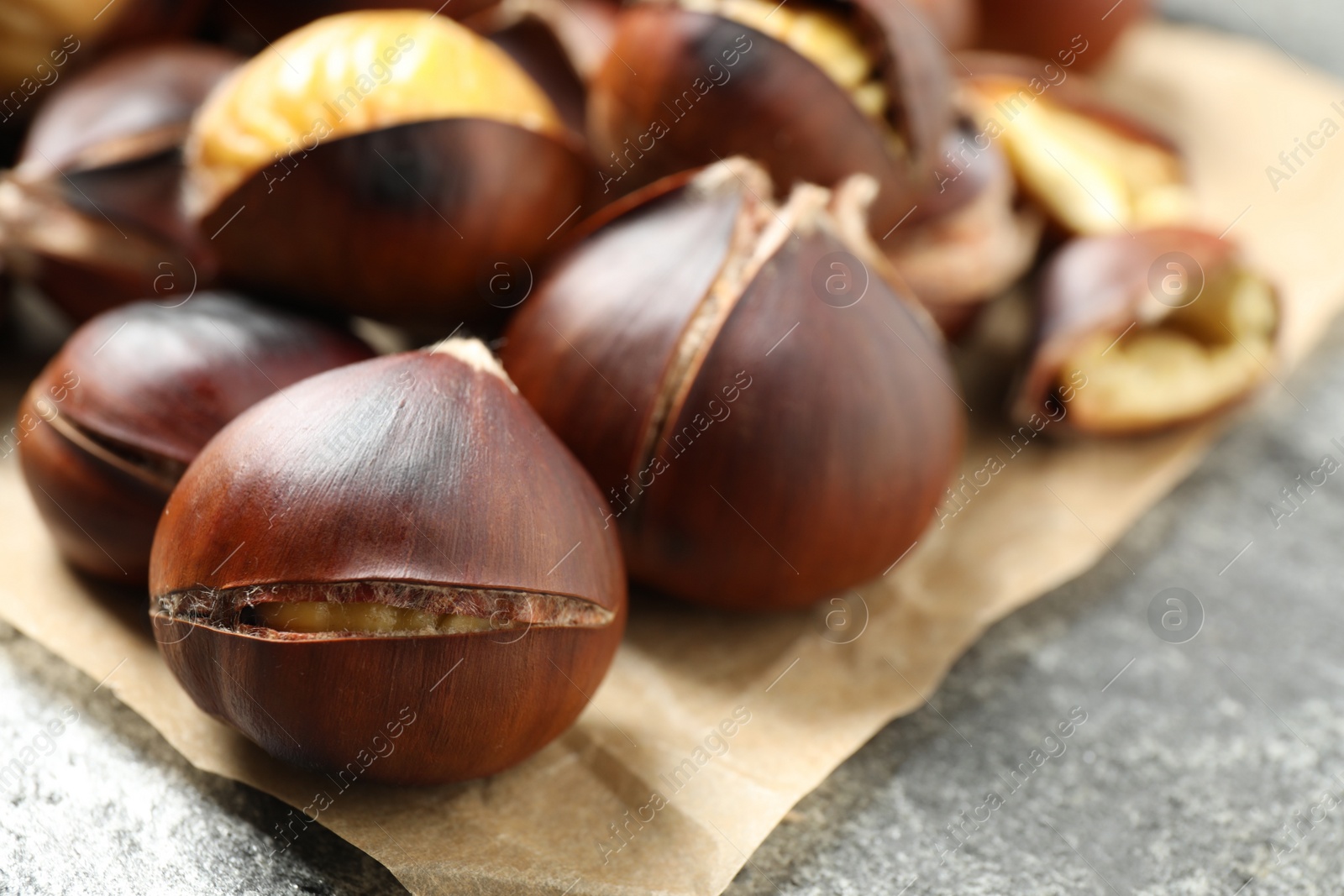 Photo of Delicious roasted edible chestnuts on grey table, closeup