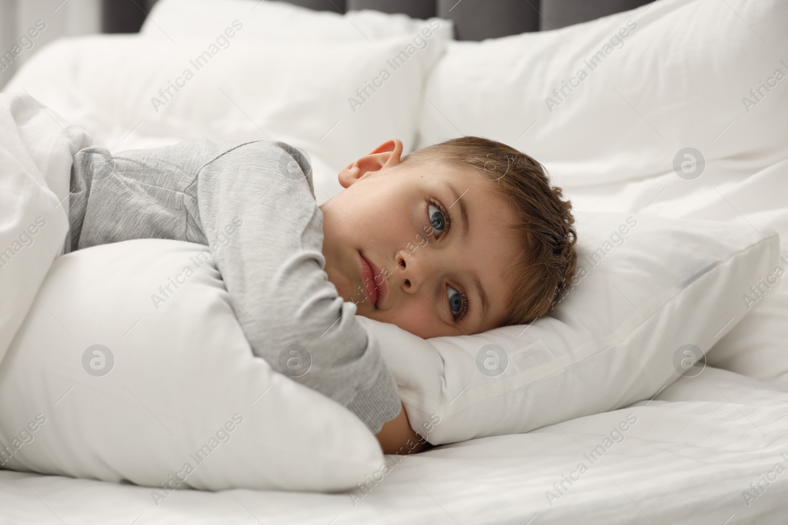 Photo of Sad little boy in bed at home